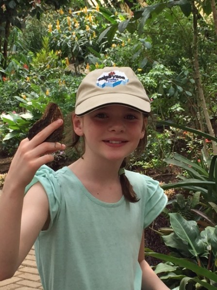 Avery holds a blue morpho butterfly inside the butterfly garden.