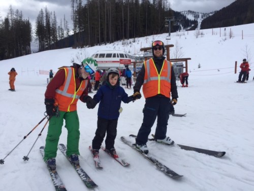 Volunteer instructors help Bennett ski to the chairlift.